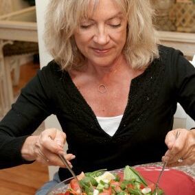 A beautiful fit woman in her fifties eating a healthy salad.
